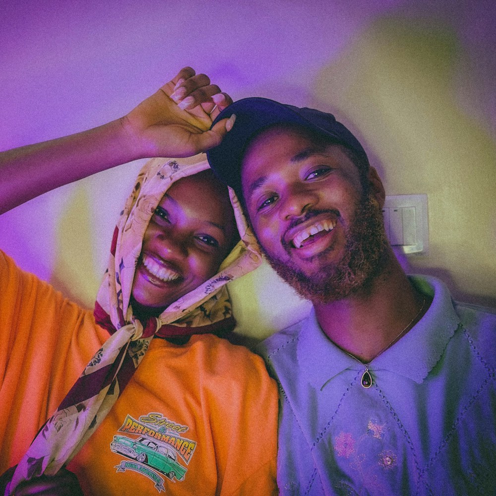 Two friends laughing together on a purple backdrop