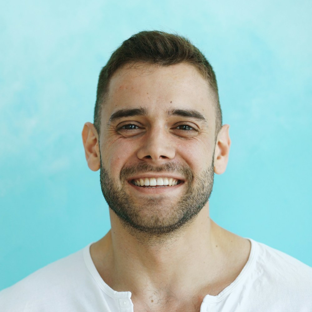 Man smiling broadly on a light blue backdrop